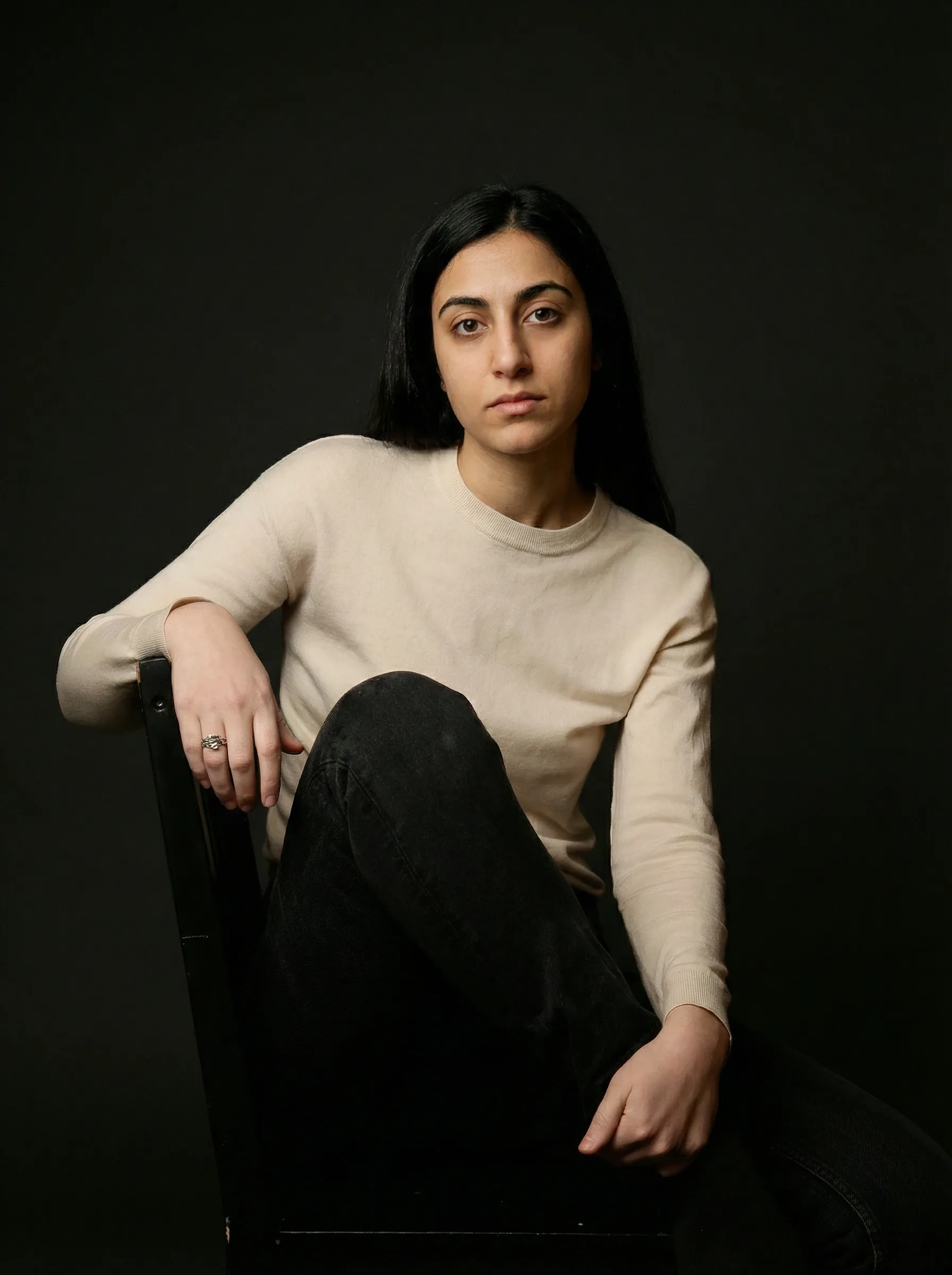 AI actress headshot — woman in a cream knit top seated against a dark studio backdrop